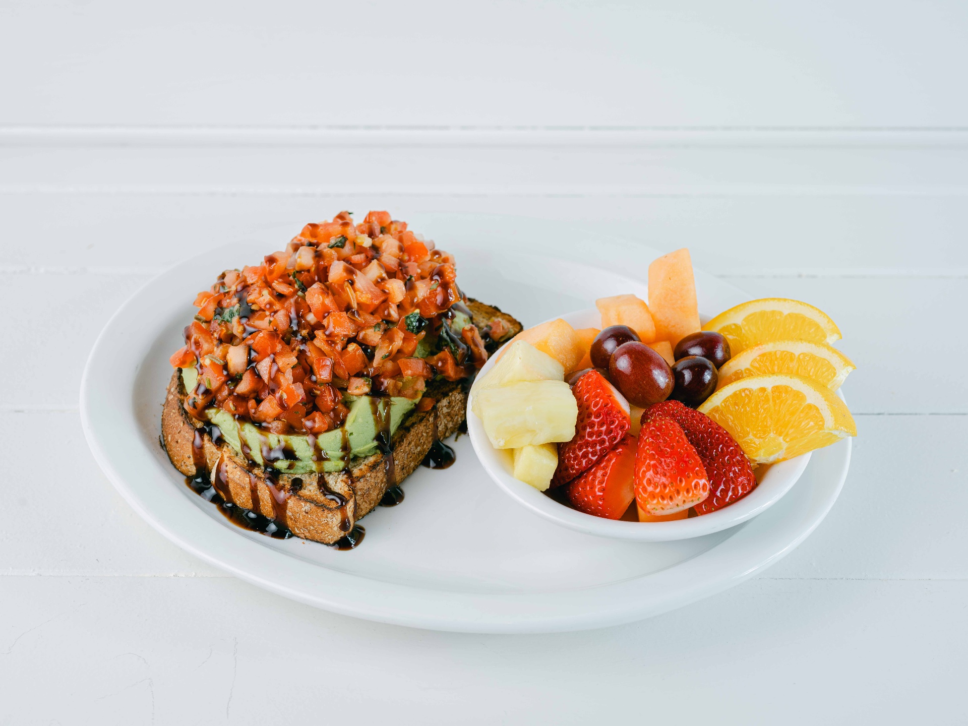 Bruschetta avocado toast with balsamic glaze and fresh fruit